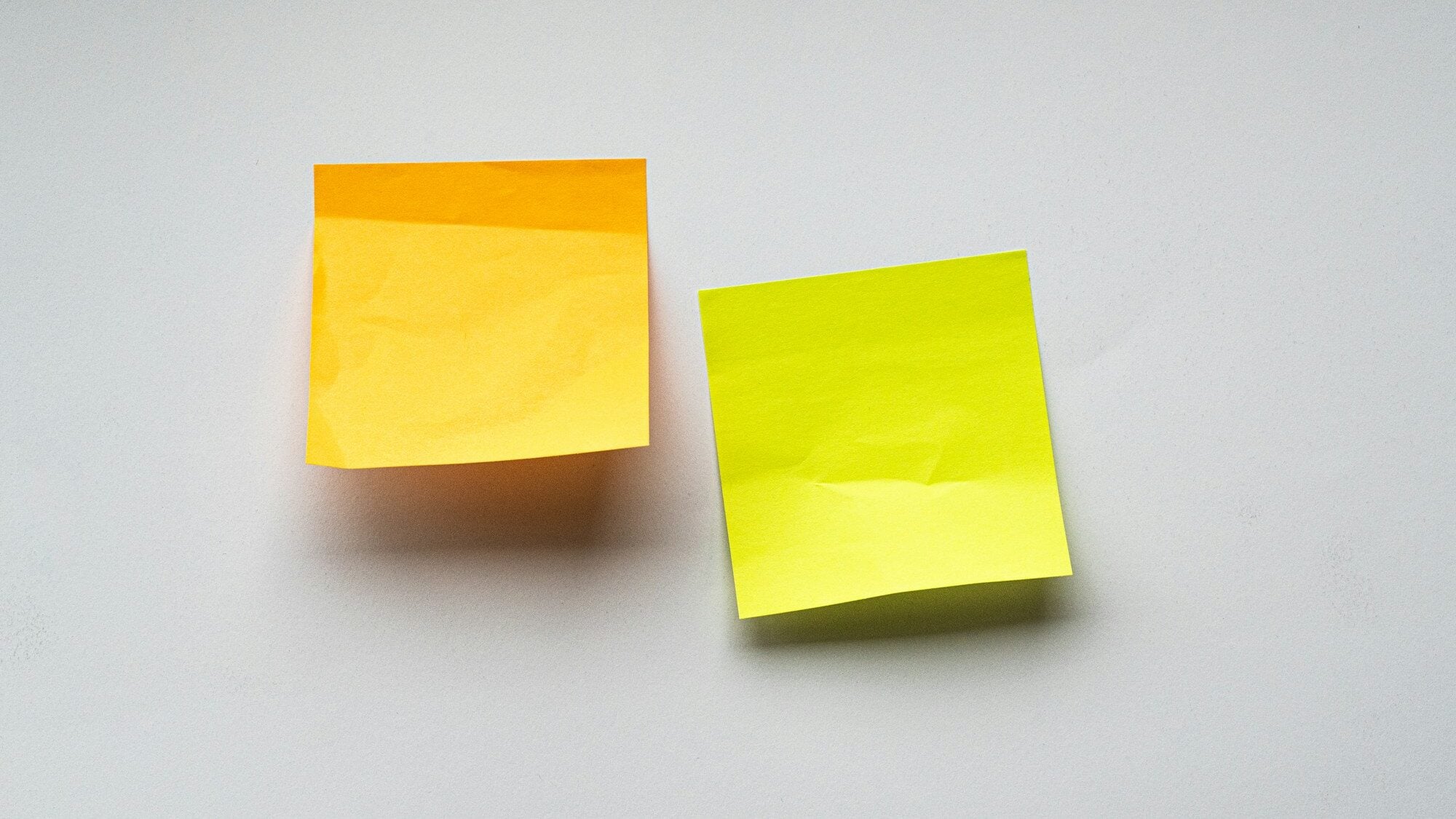 Two blank sticky notes on a white wall