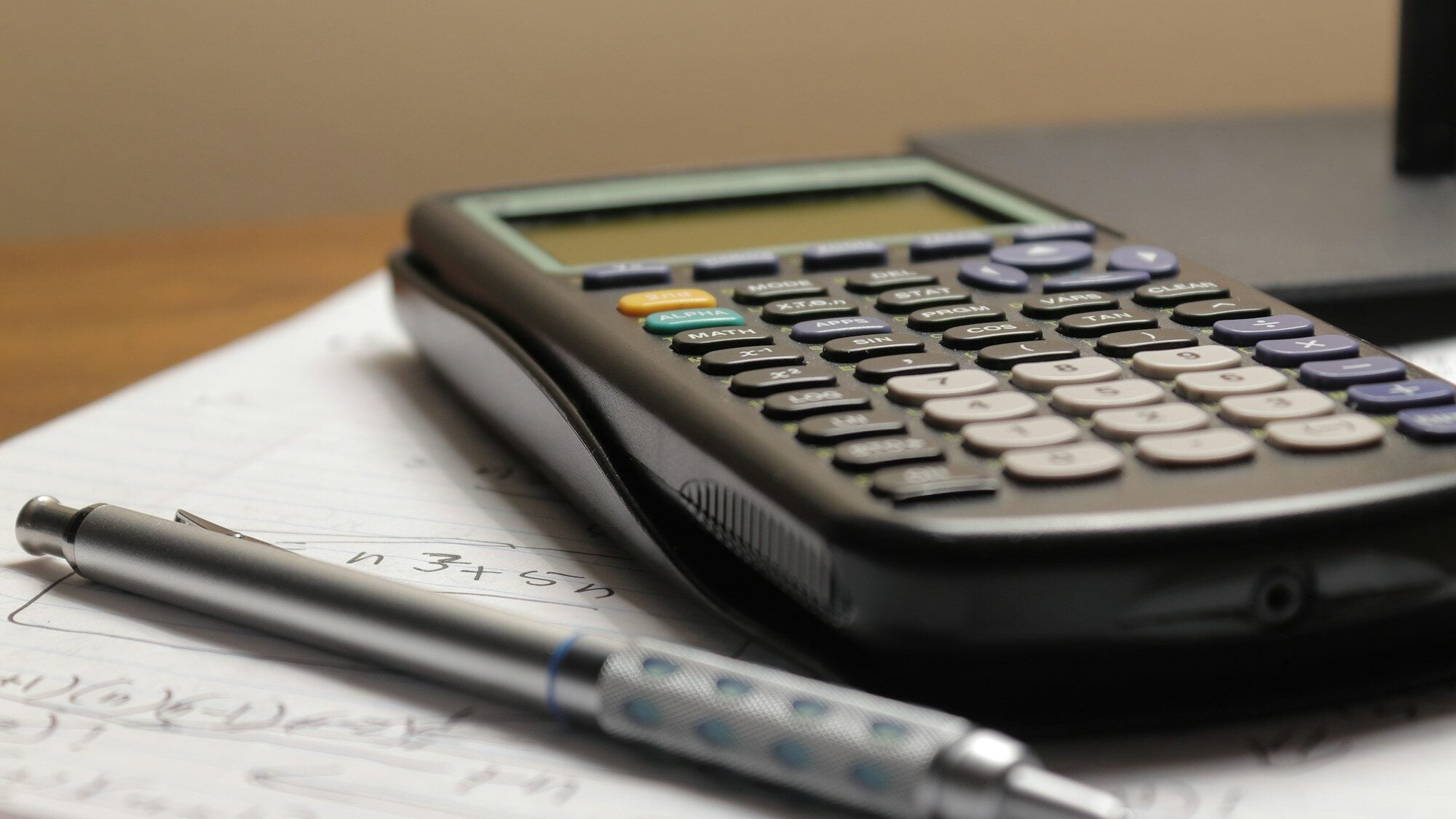 A calculator and a mechanical pencil on a sheet of handwritten notes