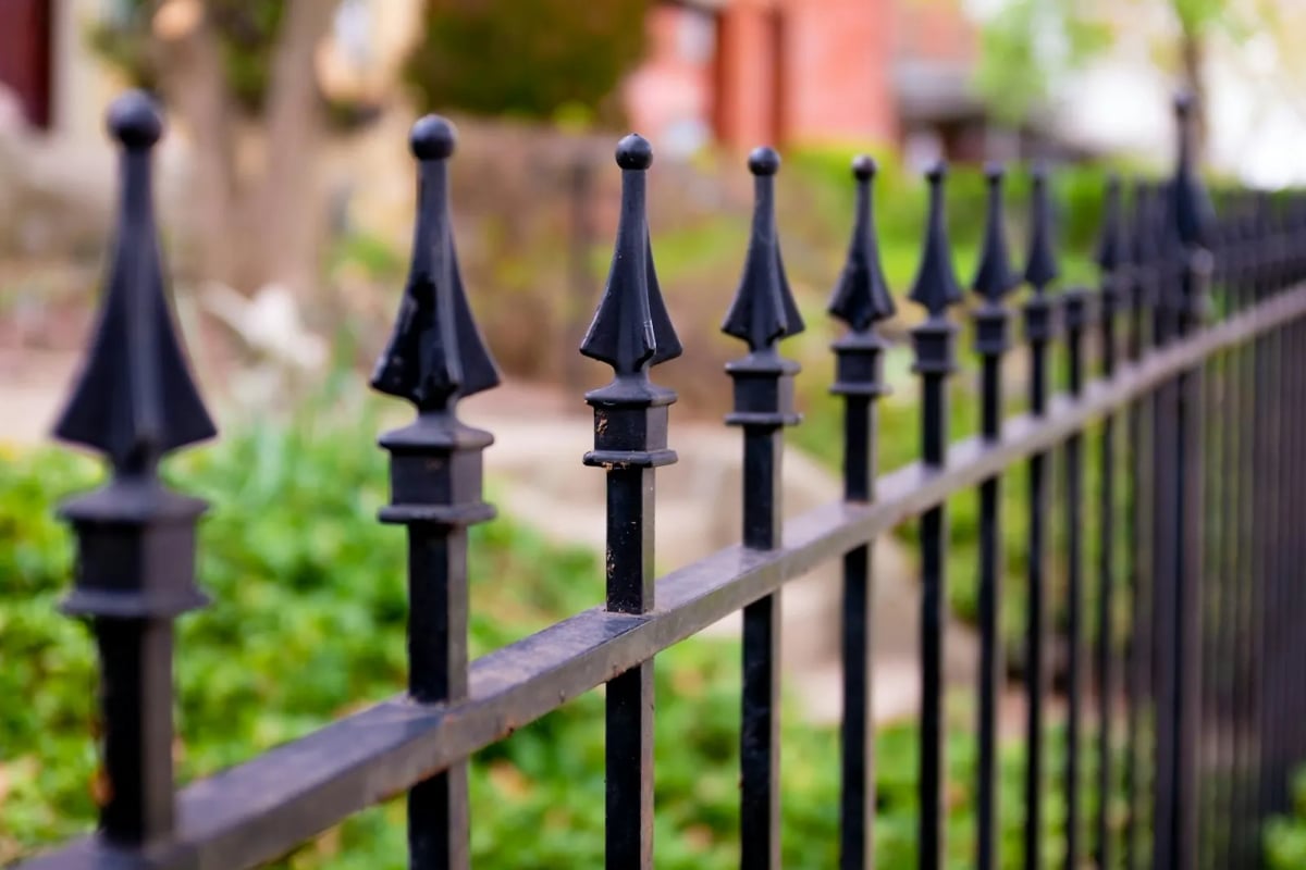 A row of black metal fence bars with pointed finials