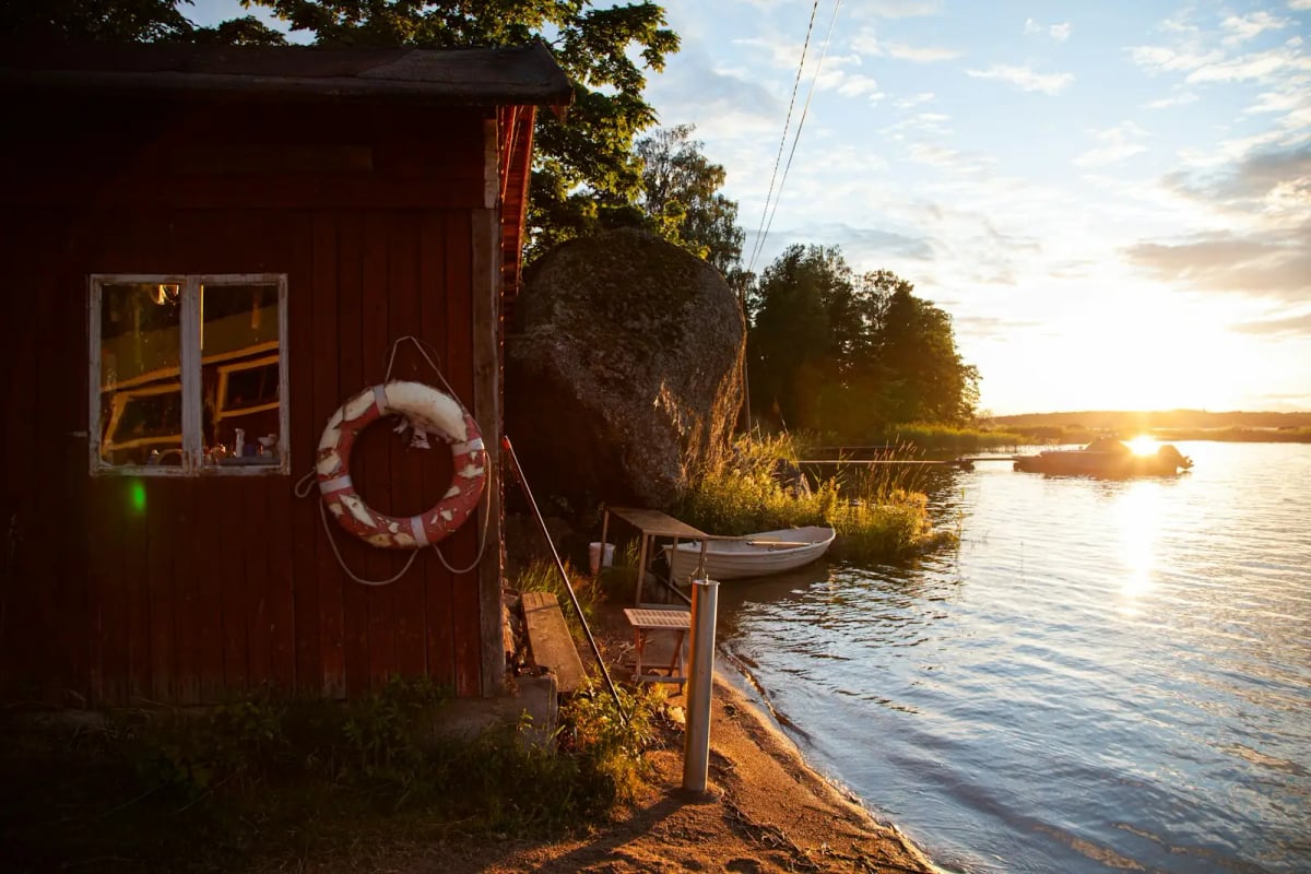Punainen pieni mökki, jossa on pelastusrengas, järven rannalla auringonlaskun aikaan