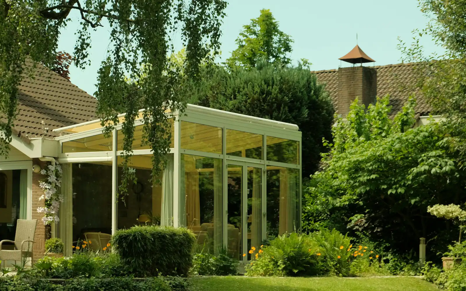 A glass veranda on a family house in a garden with trees